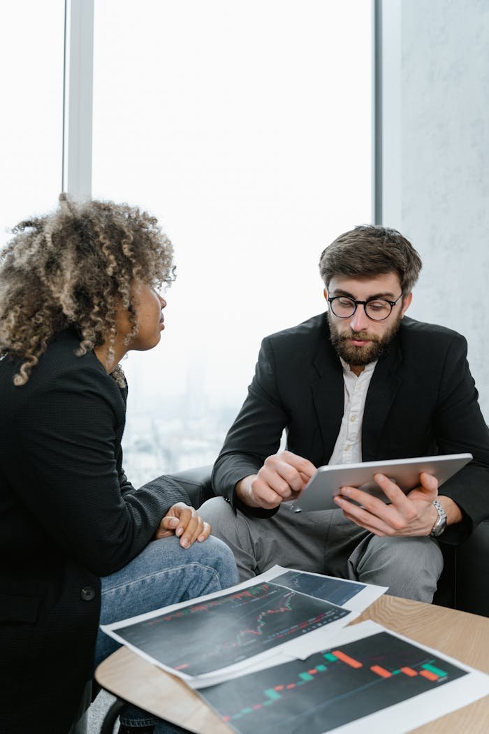 Two professionals discussing data and graphs in a modern office setting.